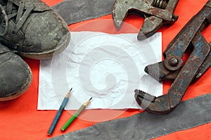 Adjustable wrenches with old boots and a sheet of paper with two pencils. Still life associated with repair, railway or plumbing