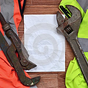 Adjustable wrenches and paper lies of an orange and green signal worker shirts. Still life associated with repair, railway or plu