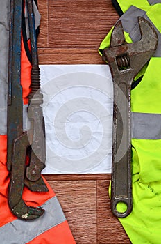 Adjustable wrenches and paper lies of an orange and green signal worker shirts. Still life associated with repair, railway or plu