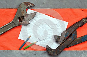 Adjustable wrenches and a sheet of paper with two pencils. Still life associated with repair, railway or plumbing work