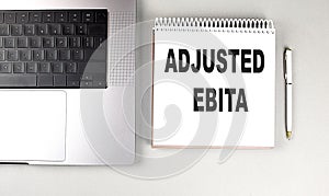 ADJUSTED EBITA text on notebook with laptop and pen photo