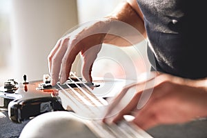 Adjusting guitar. Close-up of musician hands touching metal strings of guitar gently