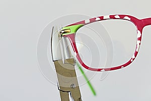 Adjusting inclination on patchy red and white children eyeglass frame.