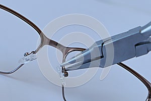 Adjusting nose pads position on metal eyeglass frame with flat snipe nose pliers.
