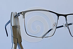 Adjusting temples on metal eyeglass frame with holding pliers equipped with replaceable nylon jaws