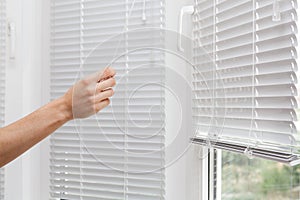 Adjusting the white blinds in height use a cord.