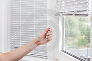 Adjusting the white blinds in height use a cord.