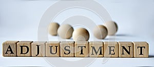 ADJUSTMENT - word on a wooden block on a white background with wooden balls
