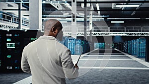 Admin walking in high tech data center facility, checking equipment