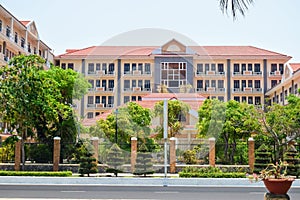 Administration building with beautiful facade behind a fence and tropical trees