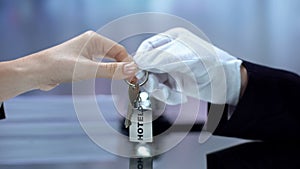 Administrator in glove giving guest keychain, visiting hotel, service quality