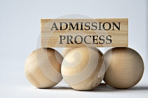 ADMISSION PROCESS - words on a wooden block on a white background with wooden balls