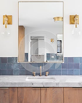 A bathroom with blue tiles and gold lights.