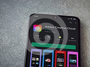 Adobe Creative Cloud app play store page on a smartphone on ceramic stone background