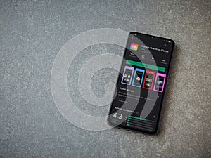 Adobe Creative Cloud app play store page on a smartphone on ceramic stone background