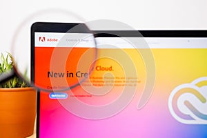 Adobe Logo under a magnifying glass. Adobe Website on Laptop screen