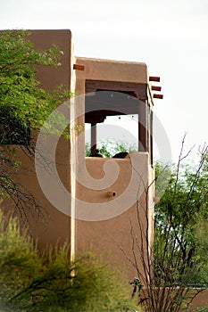 Adobe style building with flat roof and balcony with rain gutter posts and block style design in back yard neighborhood