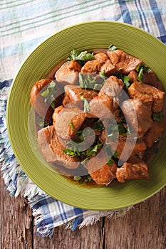 Adobo Chicken with herbs close-up on a plate. vertical top view