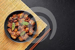Adobo Pork in black bowl at dark slate background. Pork Adobo or Adobong Baboy is filipino cuisine dish. Filipino food photo