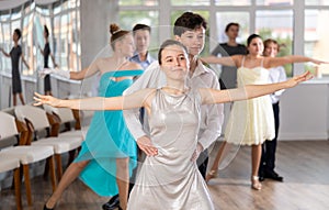 Adolescent ballroom dancers practicing elegant dance moves in pairs