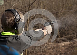 Adolescent Boy shooting pistol with smoke and brass flying