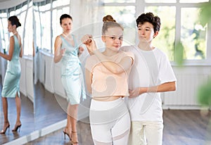 Adolescent dance duo, boy and girl, refining slow foxtrot with female coach