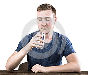 An adolescent in a dark blue T-shirt is drinking a glass of water, isolated on a white background. Medicine.