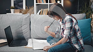 Adolescent doing homework on couch