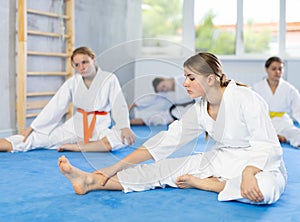 Adolescent female karateka doing stretching exercises before martial arts training