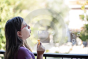 Adolescent girl blowing bubbles on the balcony