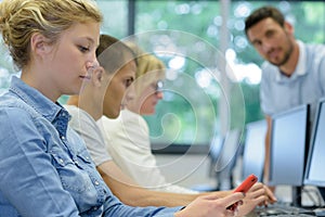 Adolescent girl using smartphone during computer class
