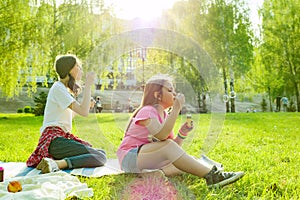Adolescent girls having fun in the park - blowing soap bubbles.