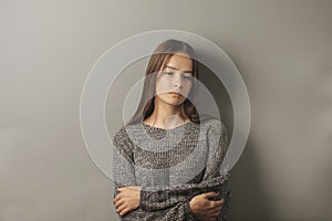 Adolescent upset, sad depressed teenager girl stands with her arms crossed, looking down