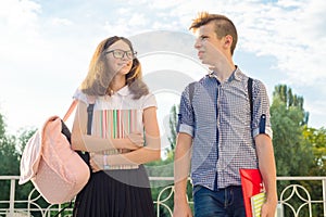 Adolescents students with backpacks, textbooks, go to school. Outdoor portrait of teenage boy and girl 14, 15 years old