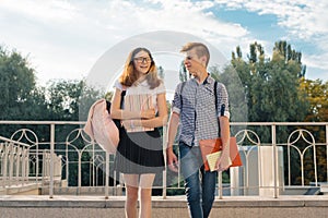 Adolescents students with backpacks, textbooks, go to school. Outdoor portrait of teenage boy and girl 14, 15 years old