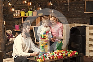 Adoption of a child. Mom, dad and kid sitting around table with colorful construction bricks. Family building a house