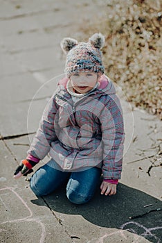 Adorabel toddler girl painted on the asphalt with a chalk, outdoor