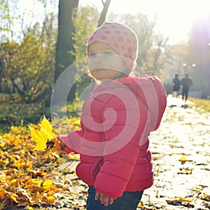 Adorabl little baby girl walking in the park in red jacket