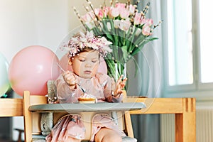 Adorable 1 year old baby girl eating cupcake