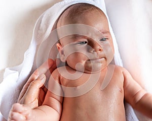 Adorable 2 months old little baby boy on towel after bath in his mother`s hands