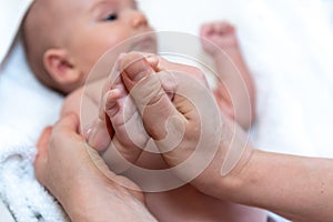 Adorable 2 months old little baby boy on towel after bath holding his mother`s hands