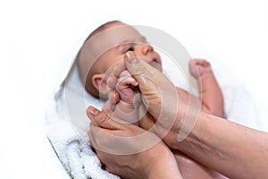 Adorable 2 months old little baby boy on towel after bath holding his mother`s hands