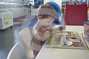 Adorable 2 years boy browsing stories at library