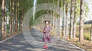 Adorable 5 years old asian girl is running in beautiful park with perspective view of concrete road as background shows kid motion
