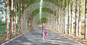 Adorable 5 years old asian girl is running in beautiful park with perspective view of concrete road as background shows kid motion