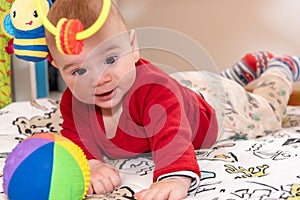 Adorable 6 months old little baby boy during tummy time surrounded by colourful toys