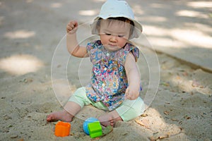 Adorable 9 months old baby playing outdoors - lifestyle portrait of mixed ethnicity Asian Caucasian baby girl playing with block