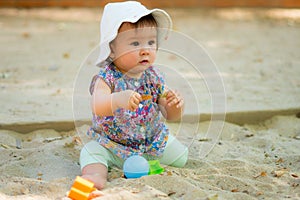 Adorable 9 months old baby playing outdoors - lifestyle portrait of mixed ethnicity Asian Caucasian baby girl playing with block