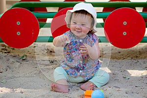 Adorable 9 months old baby playing outdoors - lifestyle portrait of mixed ethnicity Asian Caucasian baby girl playing with block