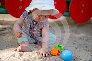 Adorable 9 months old baby playing outdoors - lifestyle portrait of mixed ethnicity Asian Caucasian baby girl playing with block